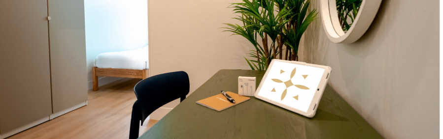 Desk with volo tablet, headphones and notebook on it on a bedroom in Daylight Recovery Center